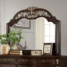 a mirror sitting on top of a dresser next to a vase with flowers in it