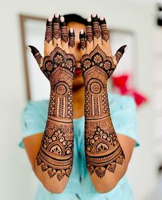 a woman holding her hands up with henna on it