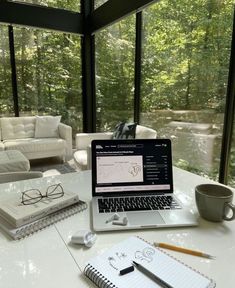 an open laptop computer sitting on top of a white table next to a cup of coffee