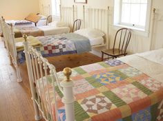 three beds in a room with wooden floors and white railings on either side of them