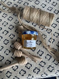 two spools of twine next to a jar of honey on a rug