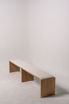 a wooden bench sitting on top of a white floor in front of a white wall