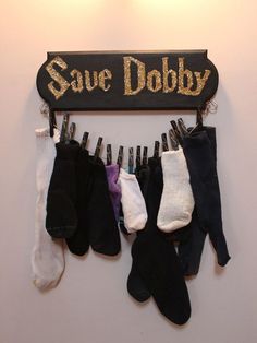 several pairs of socks hanging from a wooden sign that says save dobby on it