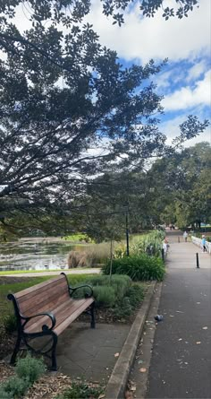 a wooden bench sitting next to a lush green park