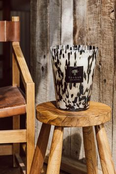 a white and black candle sitting on top of a wooden stool