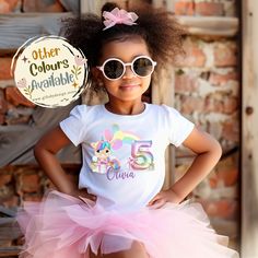 Introducing our Personalised Birthday Unicorn Party Numbers T-shirt, a magical and delightful choice for your little one's special day. This enchanting T-shirt features a charming design with a unicorn sitting amidst a pile of presents, surrounded by colorful balloons and a personalised number representing your child's age. To make it even more special, you can personalise the T-shirt with your child's name, adding a touch of uniqueness and making it a treasured keepsake. Available in a range of Playful Multicolor Unicorn Print T-shirt, Cute Unicorn Print Birthday T-shirt, Playful Pink T-shirt For Party, Pink Playful T-shirt For Parties, Birthday Unicorn Print Crew Neck T-shirt, Birthday White T-shirt With Unicorn Print, White Unicorn Print T-shirt For Birthday, White T-shirt With Unicorn Print For Birthday, Fun Unicorn Print Tops For Birthday