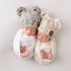 two babies are laying next to each other wearing knitted hats and scarves with bears on them