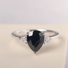 All HANDMADE ITEMS SHIP IN APPROX 8 DAYS Main Stone: Genuine natural black spinel Main Stone Size: Pear cut 7 mm x 9 mm Main Stone Weight: 2.23 carat Side Stone: Trillion cut CZ Height From The Ring Setting Bottom(to gemstone top): about 5.88 mm Width of Ring band Measure: gradually varied,about 1.28 to 2.03 mm Material: 925 Sterling Silver/14K White Gold/14K Yellow Gold/14k Rose Gold Engraved: Available For FreeNo more than 13 letters) Customized:Of course! Tell me what you want Includes With O Classic Black Sapphire Ring For Gift, Classic Black Sapphire Ring As Gift, Black Pear-shaped Jewelry For Weddings, Classic Black Jewelry For Proposal, Black Pear-shaped Wedding Jewelry, Black Drop Jewelry For Anniversary, Black Teardrop Wedding Rings, Classic Pear-shaped Jewelry For Proposals, Classic Black Pear-shaped Jewelry