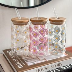 three glass tumblers with straws sitting on top of a book