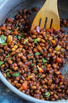 pan fried black - eyed peas with fresh herbs in it and a wooden spatula