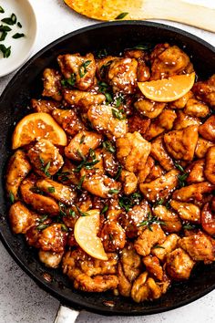 a skillet filled with chicken and orange slices