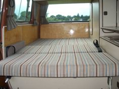 a bed in the back of a camper with two beds on each side and windows