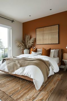 a bedroom with an orange accent wall and white bedding is pictured in this image