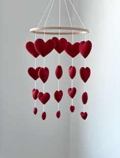 a red heart mobile hanging from a white ceiling with hearts attached to the strings in front of it