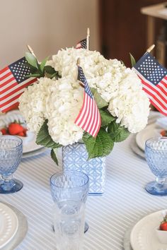 a vase filled with white flowers sitting on top of a blue and white table cloth