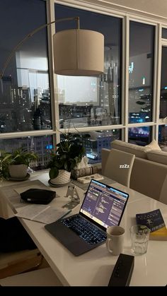 an open laptop computer sitting on top of a white table next to a large window