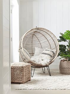 a rattan chair and two planters in a white room