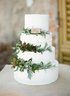 a white wedding cake with greenery on top