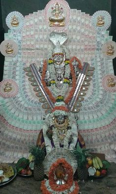 an idol is displayed in front of a wall with fruit and other decorations on it