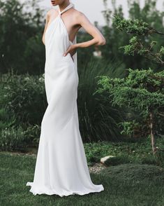 a woman in a white dress standing on grass