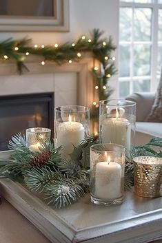 candles are lit on a tray in front of a fireplace with evergreen branches and pine cones