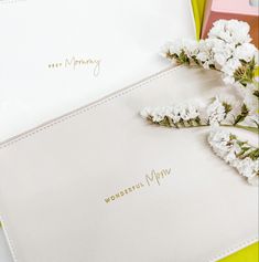 two white flowers are sitting on top of a mother's day card and envelope