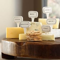 a wooden table topped with lots of cheese and crackers on top of each other