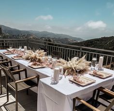 a long table set with place settings on a balcony