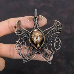 a hand holding a metal pendant with an intricate design on it's center piece