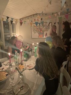 a group of people sitting at a table with balloons and candles in front of them