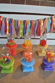 there are many jelly beans in glass jars on the table with bunting streamers