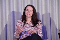 a woman sitting in a chair with her hands out and talking to someone on the other side