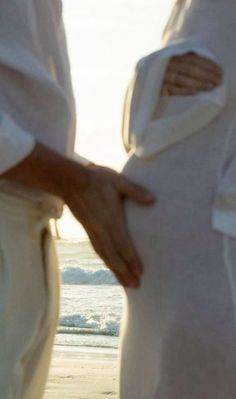 two people standing on the beach with their hands in each other's butts