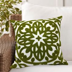 a green and white pillow sitting on top of a couch next to a potted plant