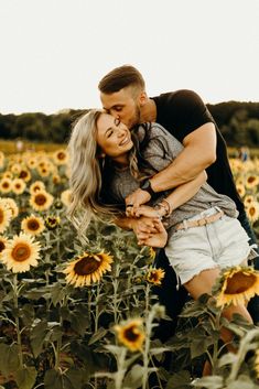 a man and woman hugging in a field of sunflowers