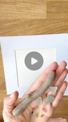 a person holding a piece of driftwood in front of a white paper with an arrow on it