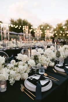 the table is set with white flowers and black napkins