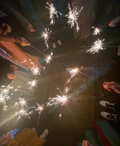 people are standing around with sparklers in their hands and feet on the ground,