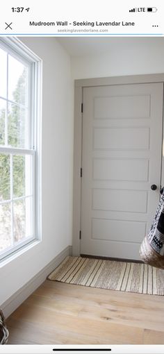 a room with a door, window and rug on the floor in front of it