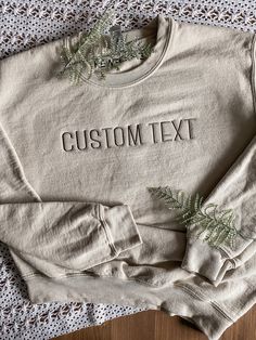 "CUSTOM TEXT EMBROIDERED APPAREL ♡ Gildan 18000 Heavy Blend Crewneck Sweatshirt T - Unisex ♡ Custom Text ♡ 100% Pre-Shrunk Cotton ♡ 40/50 Cotton/Polyester ♡ Made in the U.S. ♡ Model is wearing \"Sand\"; Size: S; Embroidery Thread: \"Brown\" IMPORTANT NOTICE: Crewnecks now have a paper like stabilizer that appears on the inside. This helps with increasing quality and ensure a longer lasting design on the sweatshirts. NOTE: Personalization will appear exactly as typed. Please ensure that all capit Cotton Crew Top With Embroidered Text, Basic Relaxed Fit Top With Custom Embroidery, Basic Cotton Tops With Custom Embroidery And Relaxed Fit, Custom Text Crew Neck T-shirt For Fall, Basic Crew Neck Tops With Letter Embroidery, Cotton Crew Neck Tops With Custom Text, Cotton Crew Top With Custom Text, Brown Embroidery, Embroidered Apparel