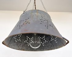 an old metal light hanging from a chain on a white wall with stars in it