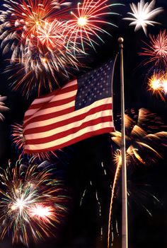 an american flag flying in front of fireworks