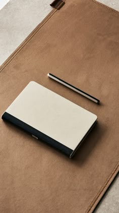 a notebook and pen sitting on top of a piece of brown paper next to each other