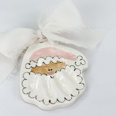 a ceramic ornament with a white ribbon around it's neck and an image of a sheep