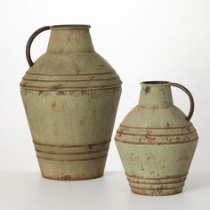 two vases sitting next to each other on a white surface with no one around them