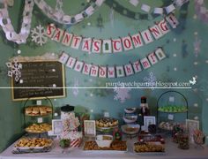 a table topped with lots of food next to a sign that says santa's coming