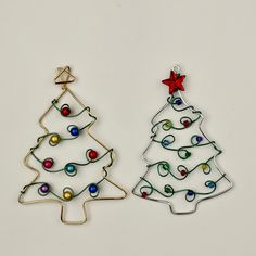 two metal christmas tree ornaments on a white surface