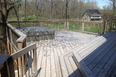 a wooden deck with an outdoor hot tub on it's side and trees in the background