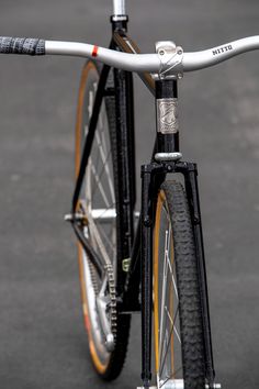 a close up of the front wheel of a bicycle on asphalt with only one tire visible