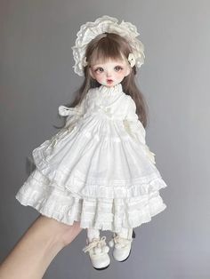 a doll is being held up in the air by a person with long hair and white dress